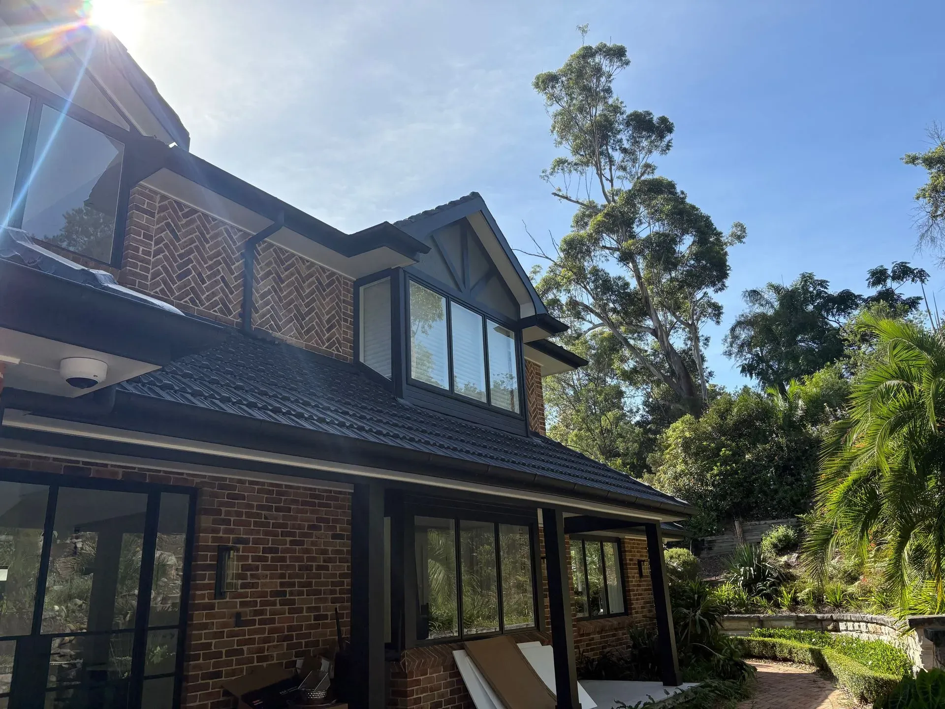 Two-storey brick home with freshly painted dark trims and eaves