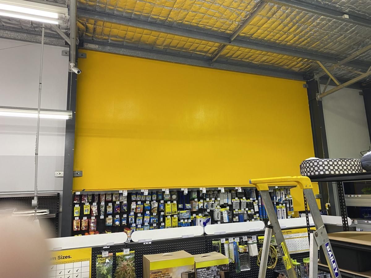 Freshly painted Petbarn yellow feature wall above the aquarium aisle, with a platform ladder in front